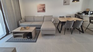 Uma sala de estar moderna com um sofá, mesa de jantar, cadeiras, uma mesa de centro e luminárias pendentes.