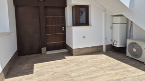 Uma escada leva a uma porta, uma pequena janela e um aparelho de ar condicionado branco.