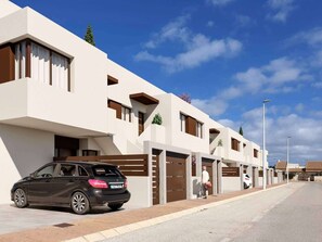 A modern residential building with a car parked in front, a clear sky, and a pedestrian pathway. - Groundfloor Beliche San Pedro Pinatar (San Pedro del Pinatar)