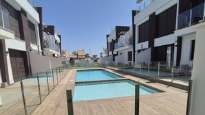 Um edifício residencial moderno com piscina e um gramado bem cuidado.