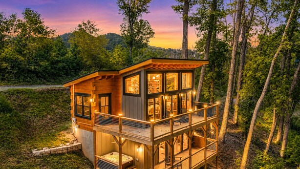 Een houten hut met een balkon, een hottub en een terras.