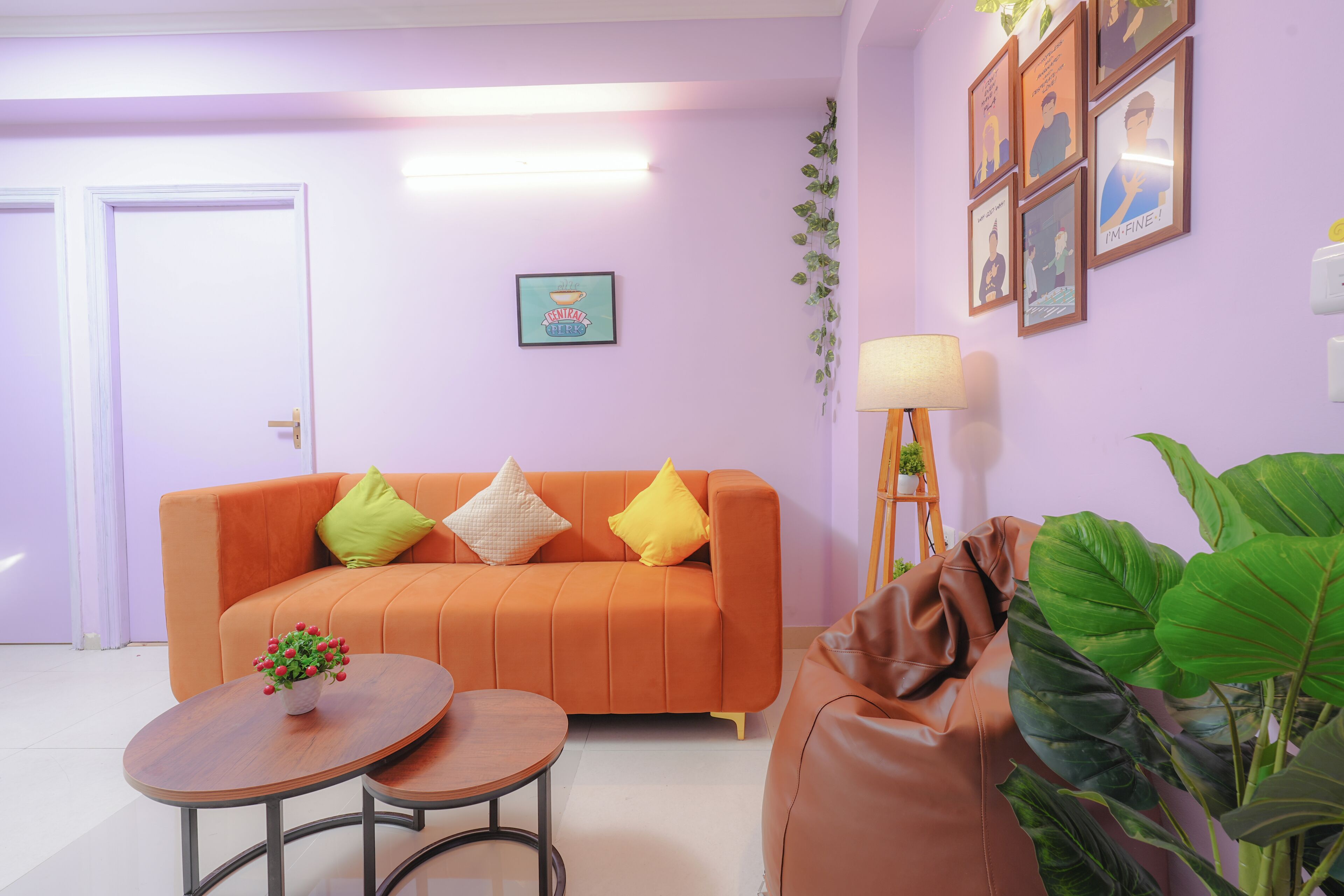Un salon avec un canapé, deux petites tables, une lampe et des tableaux encadrés accrochés au mur.