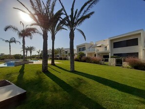 A modern two-story house with a swimming pool, surrounded by well-maintained grass and palm trees. - Penthouse Romerogolf (Pilar de la Horadada)