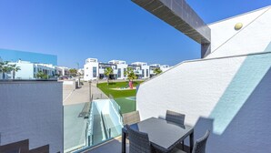 A modern building with a glass balcony overlooking a playground and residential area. - Penthouse Oasis Beach IX Punta Prima (Torrevieja)