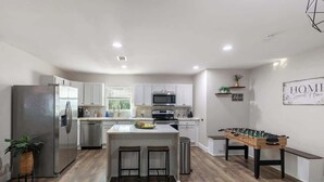 A modern kitchen with a central island, stainless steel appliances, and a foosball table. - Private 3BR Retreat in Arlington | Sleeps 8 (Arlington)