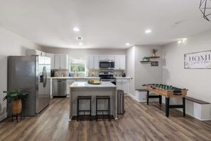 A modern kitchen with a central island, stainless steel appliances, and a foosball table. - Private 3BR Retreat in Arlington | Sleeps 8 (Arlington)