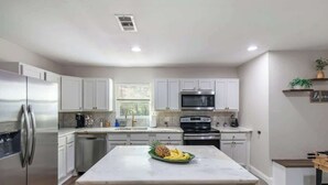 A modern kitchen with white cabinets, stainless steel appliances, and a marble island with fruit. - Private 3BR Retreat in Arlington | Sleeps 8 (Arlington)