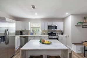 A modern kitchen with white cabinets, stainless steel appliances, and a marble island with fruit. - Private 3BR Retreat in Arlington | Sleeps 8 (Arlington)