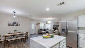 A modern kitchen with a marble island, stainless steel appliances, and a dining area with wooden furniture. - Private 3BR Retreat in Arlington | Sleeps 8 (Arlington)