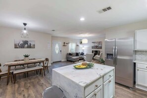 A modern kitchen with a marble island, stainless steel appliances, and a dining area with wooden furniture. - Private 3BR Retreat in Arlington | Sleeps 8 (Arlington)