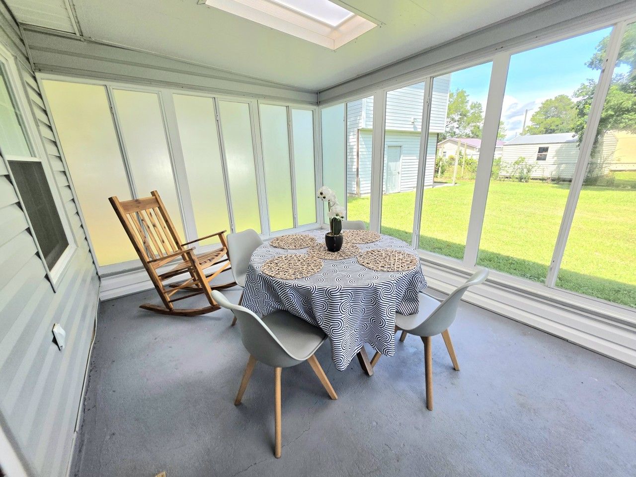 Un solárium con una mesa y sillas, ventanas amplias y vista a un jardín.