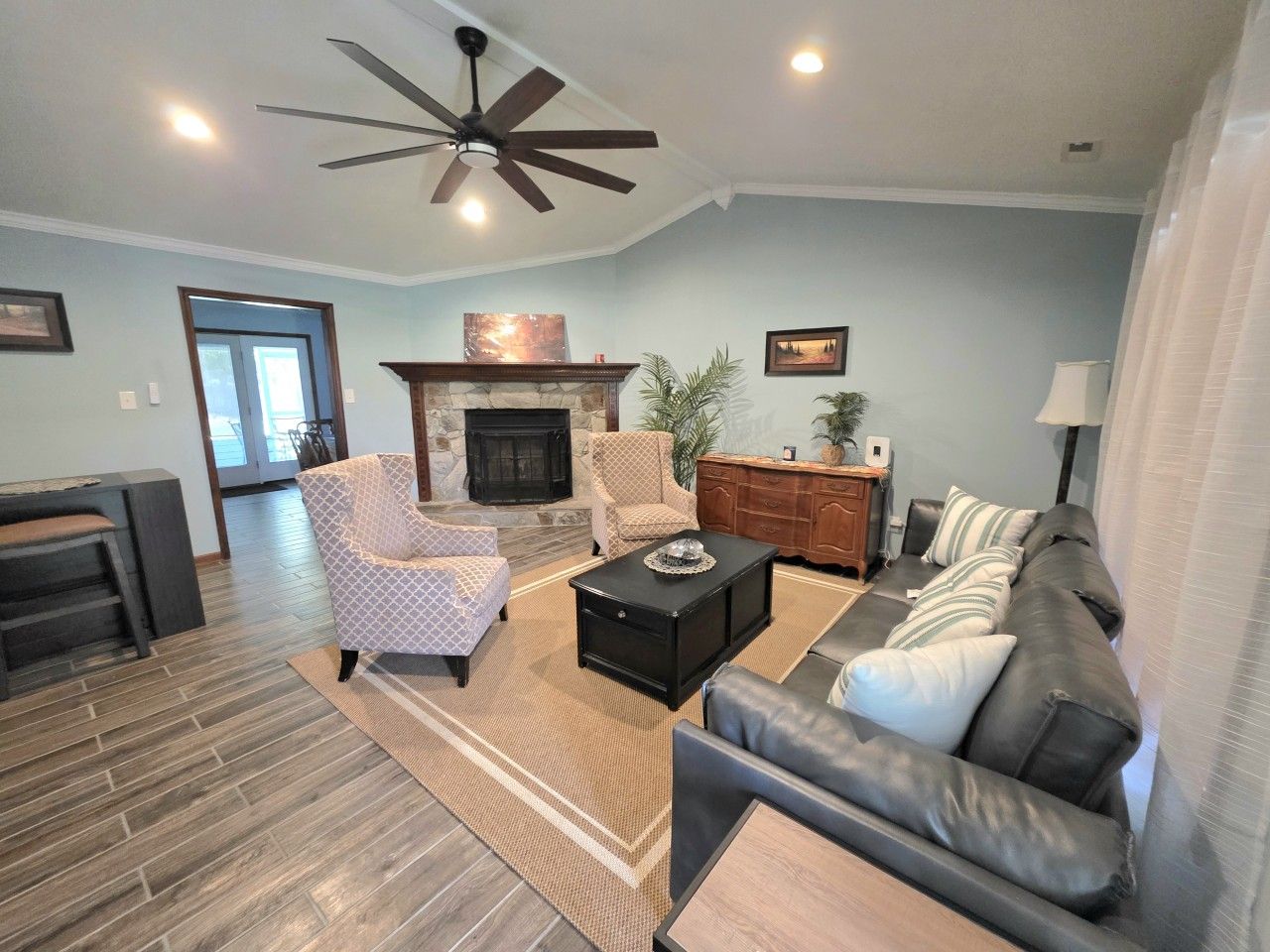 A living room with a fireplace, a sofa, a coffee table, and a ceiling fan.