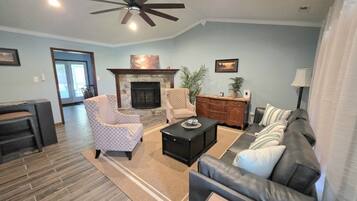 A living room with a fireplace, a sofa, a coffee table, and a ceiling fan.