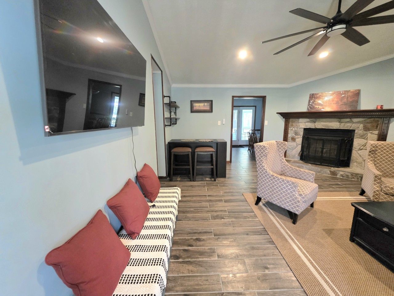 A living room with a fireplace, a ceiling fan, and a seating area with patterned sofas.