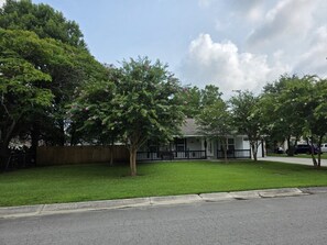 A residential property with a well-maintained lawn, a wooden fence, and a house with a porch.