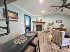 A dining area with a long table, chairs, and a fireplace.