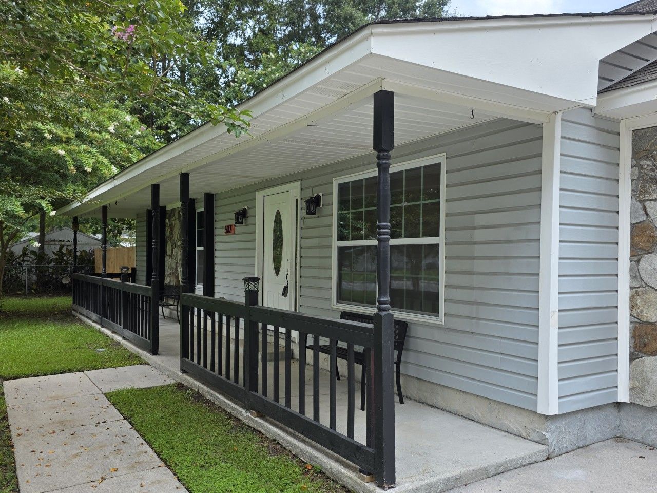 A single-story house with a covered porch, a front door, and a small window.