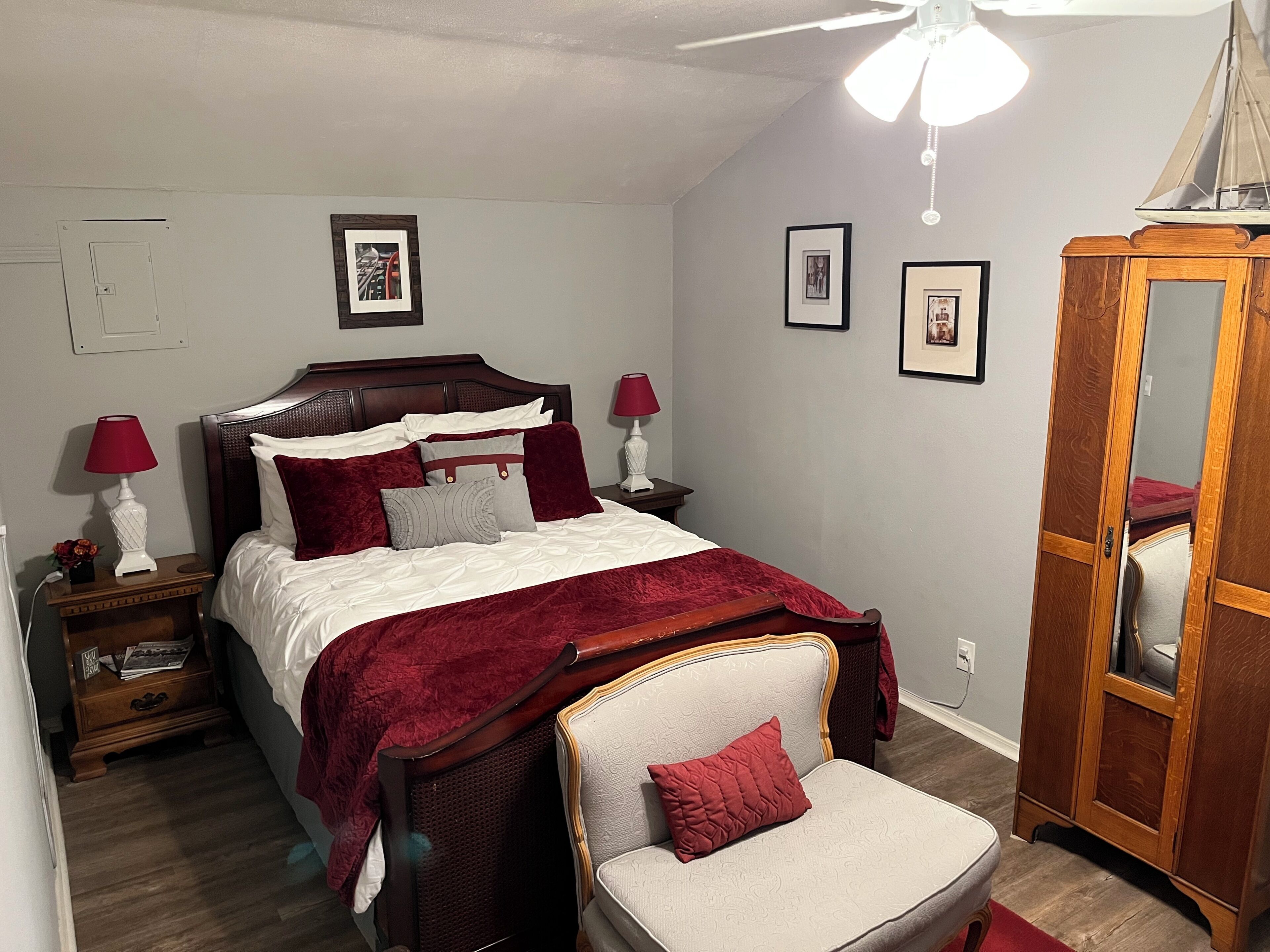 A bedroom with a bed, nightstands, a chair, a wardrobe, and a ceiling fan.
