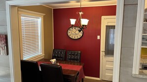 A dining area with a red wall, a clock, and a chandelier. - Desert Rose Located Near Texas Tech (Lubbock)