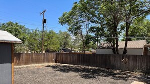 A backyard with a wooden deck, a fenced area, and a small play structure. - Desert Rose Located Near Texas Tech (Lubbock)