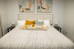 A neatly made bed with striped bedding, two bedside lamps, and abstract art on the wall. - Cozy Stay | Patio | Full Kitchen | Long Term Ready (Sandy)