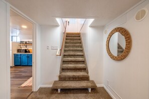 A carpeted staircase with a handrail, leading to a room with a skylight. - Cozy Stay | Patio | Full Kitchen | Long Term Ready (Sandy)