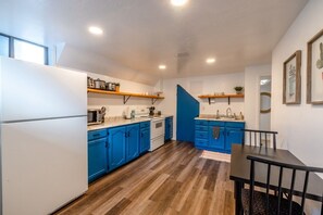 A compact kitchen with white appliances, blue cabinets, and a wooden floor. - Cozy Stay | Patio | Full Kitchen | Long Term Ready (Sandy)