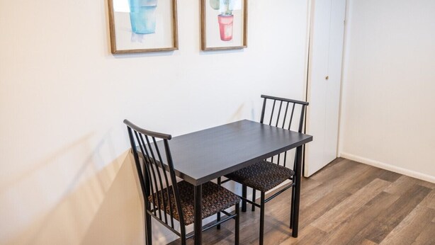 Zona pranzo con tavolo e sedie, due quadri appesi al muro e una porta.