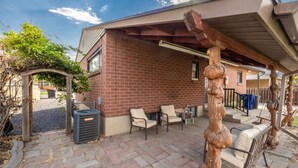 Una zona salotto esterna coperta con pareti in mattoni, una pergola e una scultura.