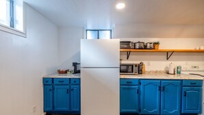 Una cucina con mobili blu, un frigorifero bianco, un forno a microonde e un piano cottura.