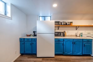 A kitchen with blue cabinets, a white refrigerator, a microwave, and a stove. - Cozy Stay | Patio | Full Kitchen | Long Term Ready (Sandy)