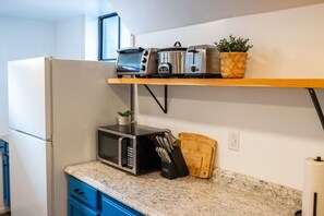 Een keuken met een magnetron, broodrooster en een plankje met een plant.