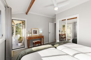 Ein Schlafzimmer mit Bett, Schreibtisch, Stuhl und einer Tür, die auf einen Balkon führt.