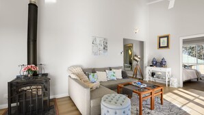 A living room with a sofa, ottoman, coffee table, and a fireplace. - Highview - Luxury Holiday Home in Nelson Bay (Nelson Bay)