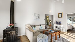 A living room with a sofa, ottoman, coffee table, and a fireplace. - Highview - Luxury Holiday Home in Nelson Bay (Nelson Bay)