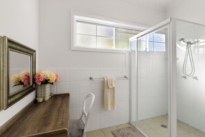 Un baño con ducha, espejo, toallero y ventana.