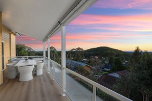 Un balcón con comedor y vista a un barrio residencial al atardecer.