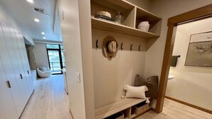 A hallway with a bench, shelves with items, and a wall-mounted hat rack. - Clubhouse & Pool Amenities, 40 Mins to Glacier NP (Whitefish)