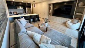 A modern living room with a sofa, coffee table, and TV. - Clubhouse & Pool Amenities, 40 Mins to Glacier NP (Whitefish)