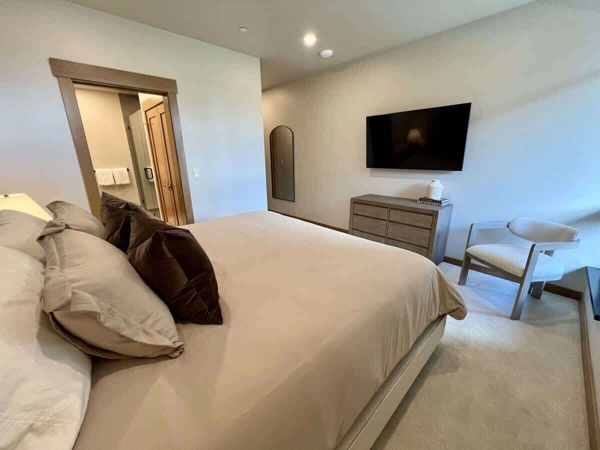 A bedroom with a bed, a chair, a television, and a dresser.