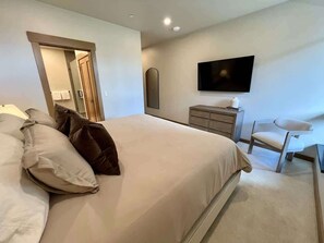 Ein Schlafzimmer mit Bett, Sessel, Fernseher und Kommode.