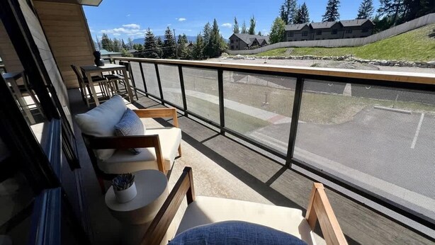 A balcony with seating, a view of a residential area, and a clear sky. - Clubhouse & Pool Amenities, 40 Mins to Glacier NP (Whitefish)
