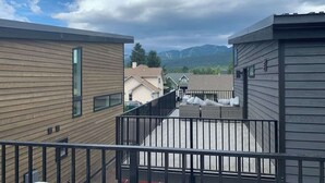 En boligbygning med balkon, udsigt til bjerge og en klar himmel.