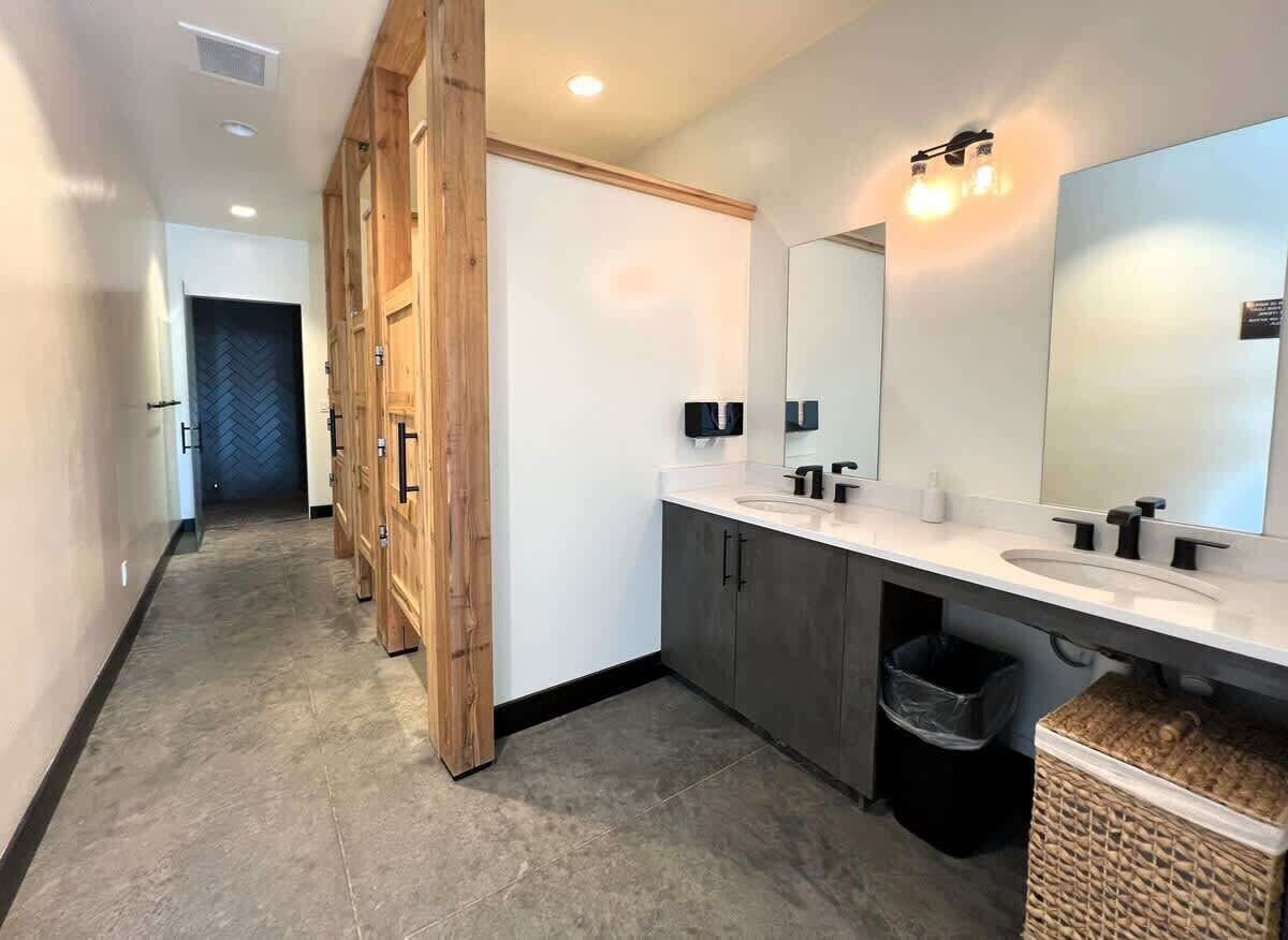 Een moderne badkamer met een grote spiegel, een dubbele wastafel en houten kastjes.