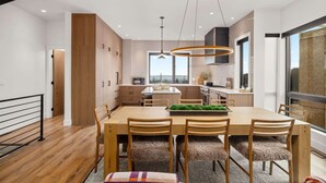 A modern kitchen with a central island, wooden cabinets, and a large window providing a view. - Luxury Ski-In&Out | Private Spa | Mountain Views (Whitefish)