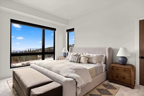 Ein Schlafzimmer mit einem großen Bett, zwei Nachttischen, einer Bank und Blick auf eine verschneite Landschaft.