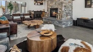 A modern living room with a stone fireplace, comfortable seating, and a flat-screen TV. - Clubhouse & Pool Amenities, 40 Mins to Glacier NP (Whitefish)