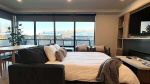 A modern hotel room with a large bed, a sofa, a dining table, and a TV. - Clubhouse & Pool Amenities, 40 Mins to Glacier NP (Whitefish)