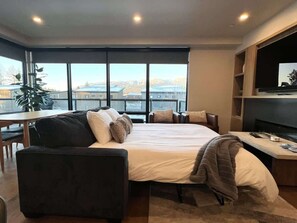 Ein modernes Hotelzimmer mit einem großen Bett, einer Couch, einem Esstisch und einem Fernseher.