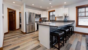 A modern kitchen with a central island, stainless steel appliances, and a bar seating area. - Downtown Condo, Sleeps 7, 35 Mins to Glacier Park (Whitefish)